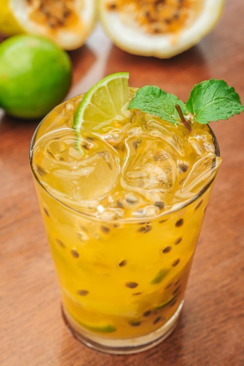 Copo de caipirinha de maracujá refrescante com gelo e hortelã