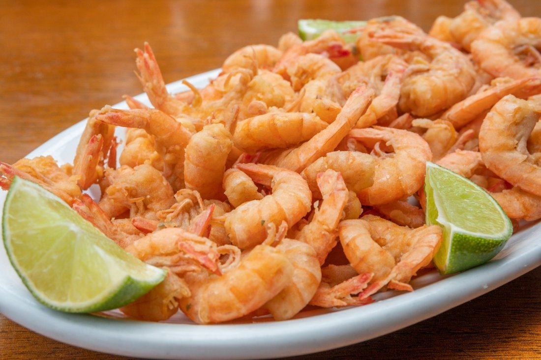 Porção farta de camarão frito inteiro com fatias de limão