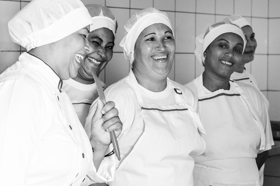 Cozinheiras da equipe do Tia Lena rindo juntas na cozinha
