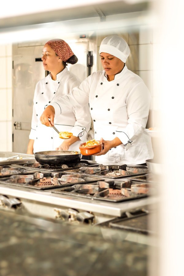Cozinheiras atentas finalizando os pratos no fogão industrial